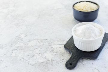 Rice flour in a white bowl on a dark board. Healthy food concept. Horizontal orientation, copy space.