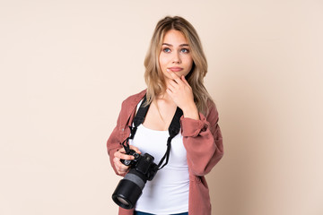 Young photographer girl over isolated background having doubts and with confuse face expression