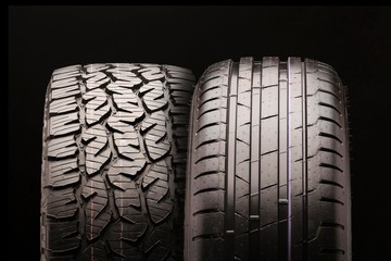 a mud tire for pickups and trucks and a passenger tire side by side together, for summer. Two...