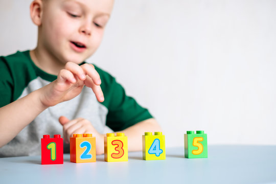 Children's cubes with numbers on the table. On the background the child counts the cubes with his finger.Isolated