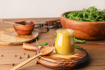 Jar of tasty honey mustard sauce on wooden table