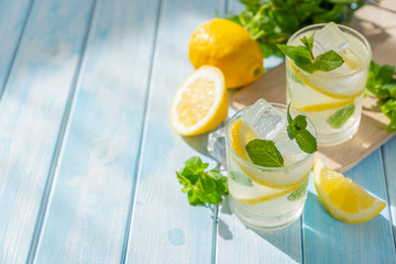 Lemonade and ingredients on blue wood background, copy space