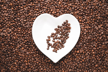 Heart-shaped plate on roasted coffee beans