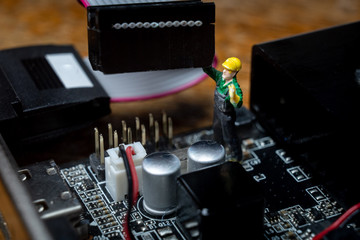 Fototapeta na wymiar Miniature workers repairing computer hardware