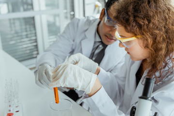 Young scientist researcher examining chemical liquid in test tube in modern laboratory. Science and medicine concept