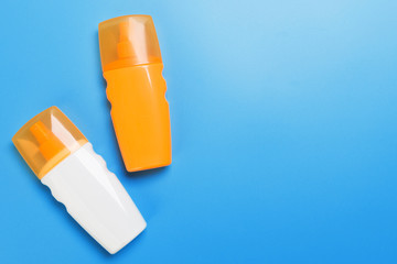 flat lay concept of summer travel vacation. Sunscreen bottle mock up on blue background top view with copy space