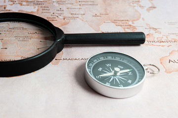 Compass and magnifying glass on the map. The oldest navigation device to navigate the world....