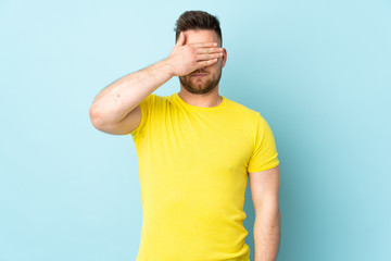 Russian handsome man isolated on blue background covering eyes by hands. Do not want to see something
