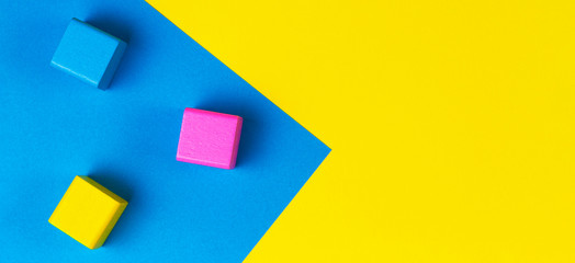 Wooden colorful blocks on geometric yellow and blue background. Top view, flat lay