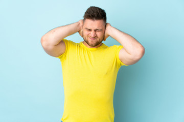 Fototapeta na wymiar Russian handsome man isolated on blue background frustrated and covering ears