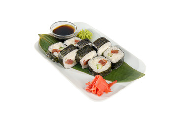 Sushi, rolls, hosomaki with salmon, avocado, cucumber and philadelphia cheese, raw seafood, soy sauce, marinated ginger and wasabi. Food on a banana leaf, white isolated background, side view