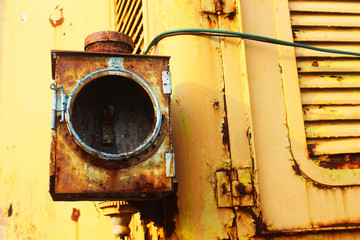 The damaged right front light of an old locomotive