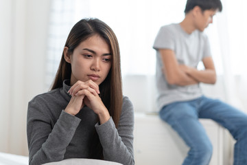 Lover couple relationship problems. Sad young wife sitting on the bed back to back from husband after argument.