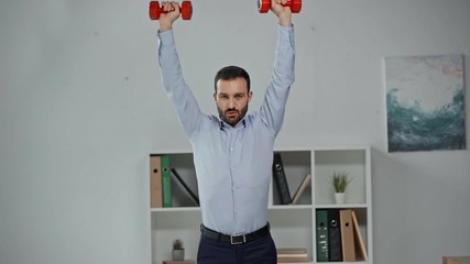 handsome businessman exercising with dumbbells in office - Powered by Adobe