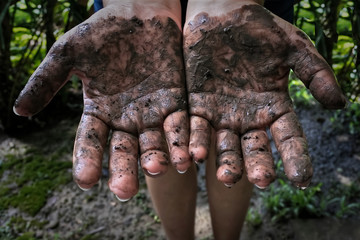 Woman standing with muddy hands from gardening
