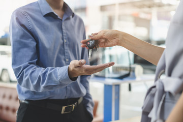 Concept car rental service. Close up view hands of agent giving car key to client that rent a...