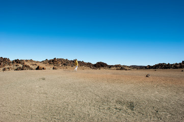 Landscape of the ancient Caldera of the Teide volcano. A girl in yellow is walking in the distance.