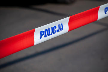 Red and white protection tape with "POLICJA" inscription. Polish police "do not cross" tape