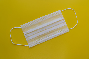 Photo of a white medical face mask against a virus on a yellow background