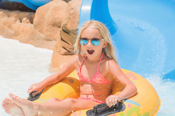 Child on water slide at aquapark. Summer holiday.