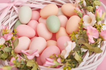 Naklejka na ściany i meble Colorful easter eggs in nest on pastel color background with flowers, copy space. Easter decorations. Easter background with painted eggs in nest, vintage style, top view. Spring greeting card