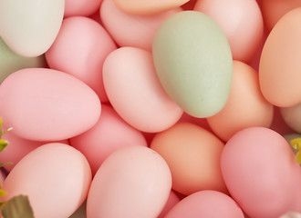 Colorful easter eggs in nest on pastel color background with flowers, copy space. Easter decorations. Easter background with painted eggs in nest, vintage style, top view. Spring greeting card