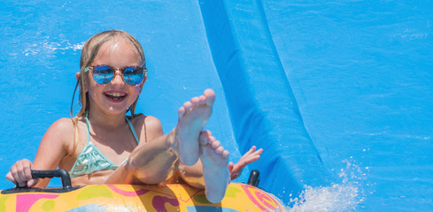 Child on water slide at aquapark. Summer holiday.