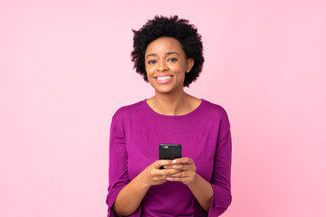 African american woman over isolated pink background sending a message with the mobile