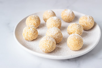 Traditional Indian festival sweets (Laddoo or Laddu) with coconut flakes on a ceramic plate, light background, selective focus. Popular tea time sweet snack in India.