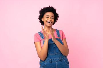 African american woman with overalls over isolated pink background applauding