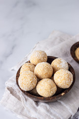 Healthy vegetarian balls with chickpea, peanut butter and coconut in the wooden bowl. Light grey background, selective focus.
