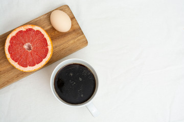 Top view of fat burning breakfast with black Americano coffee, grapefruit and boiled egg. Concept of low calorie diet with cope space for your text 