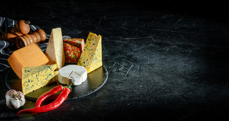 Obraz na płótnie Canvas Assortment of cheeses on dark background