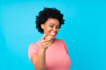 African american woman over isolated blue background points finger at you