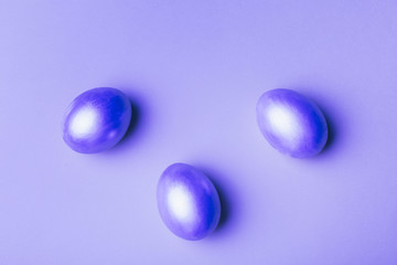 Silver easter eggs on a purple background in neon light.