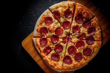 Pepperoni Pizza with Mozzarella cheese, salami, Tomato sauce, pepper, Spices. Italian pizza on Dark grey black slate background