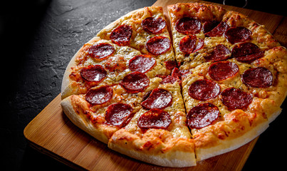 Pepperoni Pizza with Mozzarella cheese, salami, Tomato sauce, pepper, Spices. Italian pizza on Dark grey black slate background