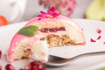 Pink mousse cake with strawberry  and a cup of coffee on a gray concrete background. side view, selective focus, bitten off.