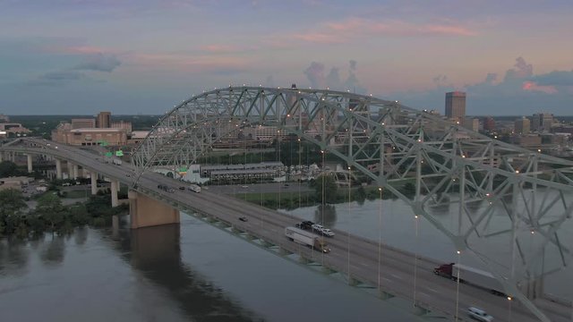 Aerial flying over traffic on the Hernando de Soto Bridge that crosses the Mississippi River at sunset. In the background is downtown Memphis, Tennessee, USA