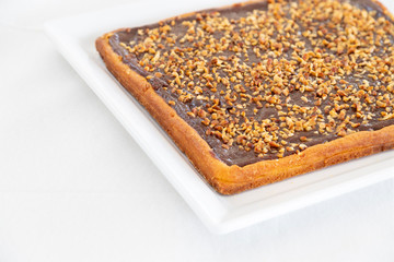 Homemade rustic style tart with nutella and chopped hazelnuts. Italian dessert. White background and copyspace