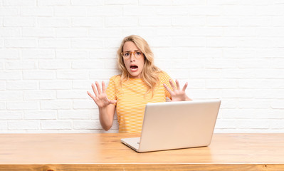 young blonde woman feeling terrified, backing off and screaming in horror and panic, reacting to a...