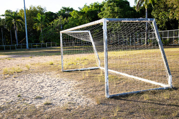 Old grunge football goal on dry grass field in soccer stadium on blurred nature background