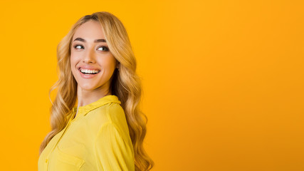 Happy blonde woman looking aside at free space
