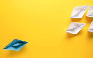 Teamwork business concept with paper boat on yellow background