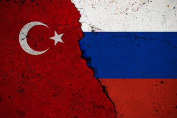 Concrete slab with large cracks, flags of Turkey and Russia. Abstract concept of a break in...