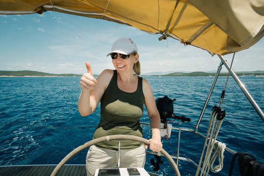 Female skipper on the steering wheel of a yacht. Sailing and yachting concept.