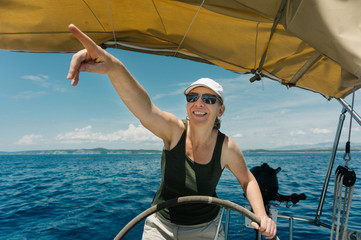 Female skipper on the steering wheel of a yacht. Sailing and yachting concept.