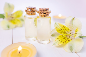 Obraz na płótnie Canvas The concept of aromatherapy, spa. Bottles with floral essential oil on a white wooden background. Nearby is a yellow flower, candles. Cozy still life in bright colors.