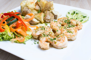 Garlic shrimp, bathed in garlic sauce, accompanied by potatoes and vegetables