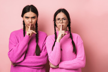 Image of two young girls keeping fingers at lips and asking to be quiet